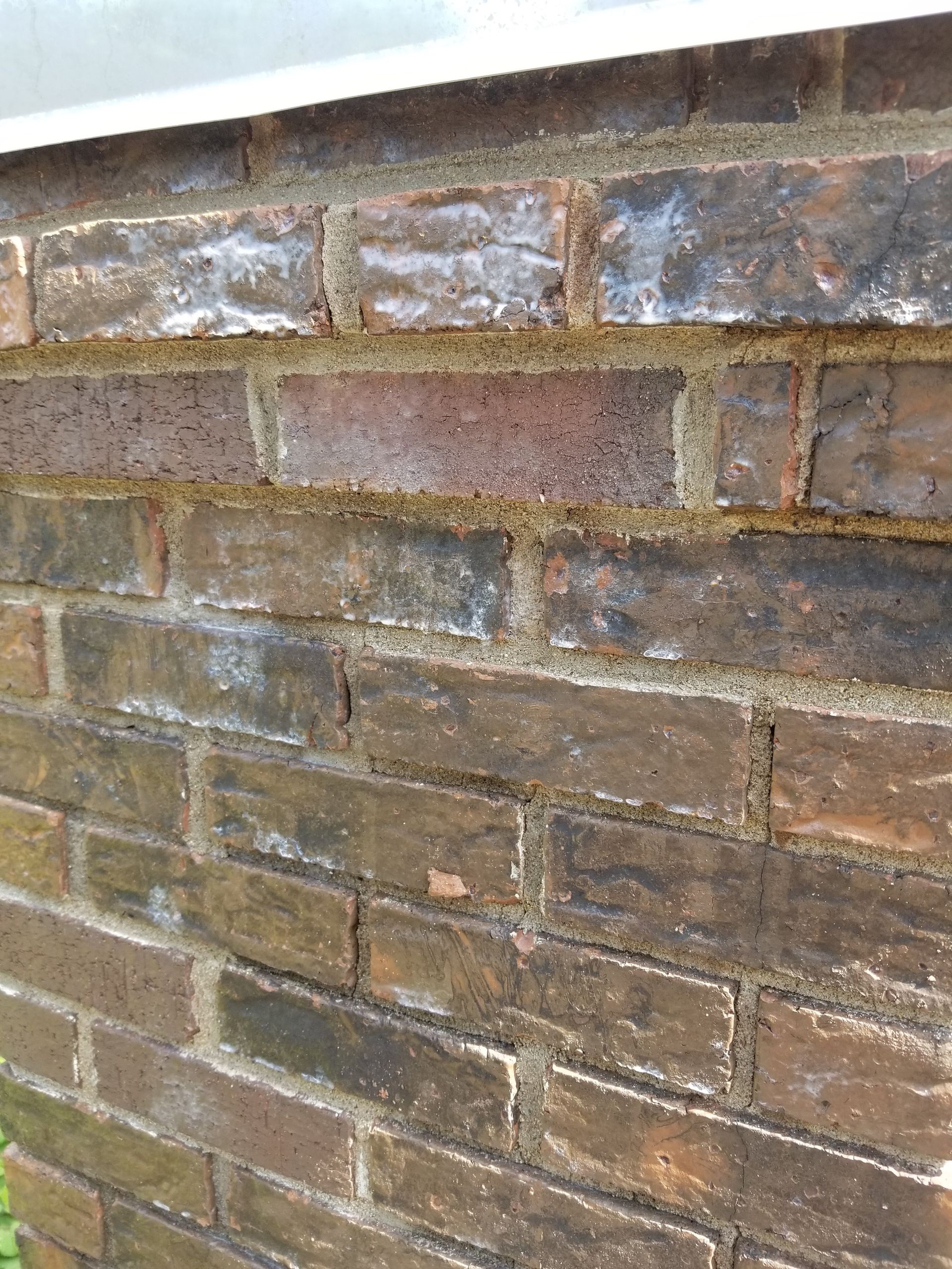 A close up of a brick wall with a white trim.