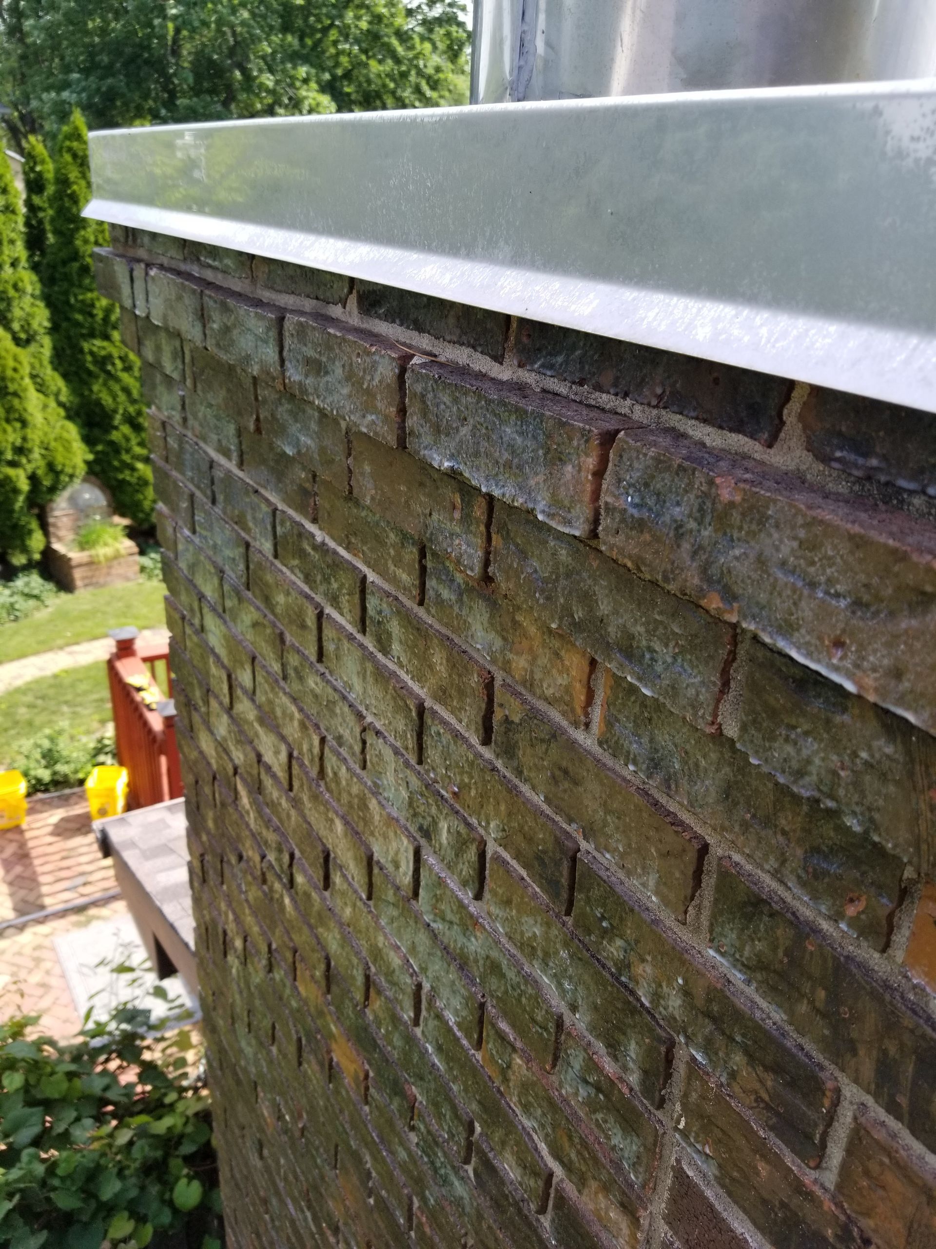 A close up of a brick wall with a metal gutter on it.