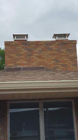 A brick chimney on top of a roof next to a window.