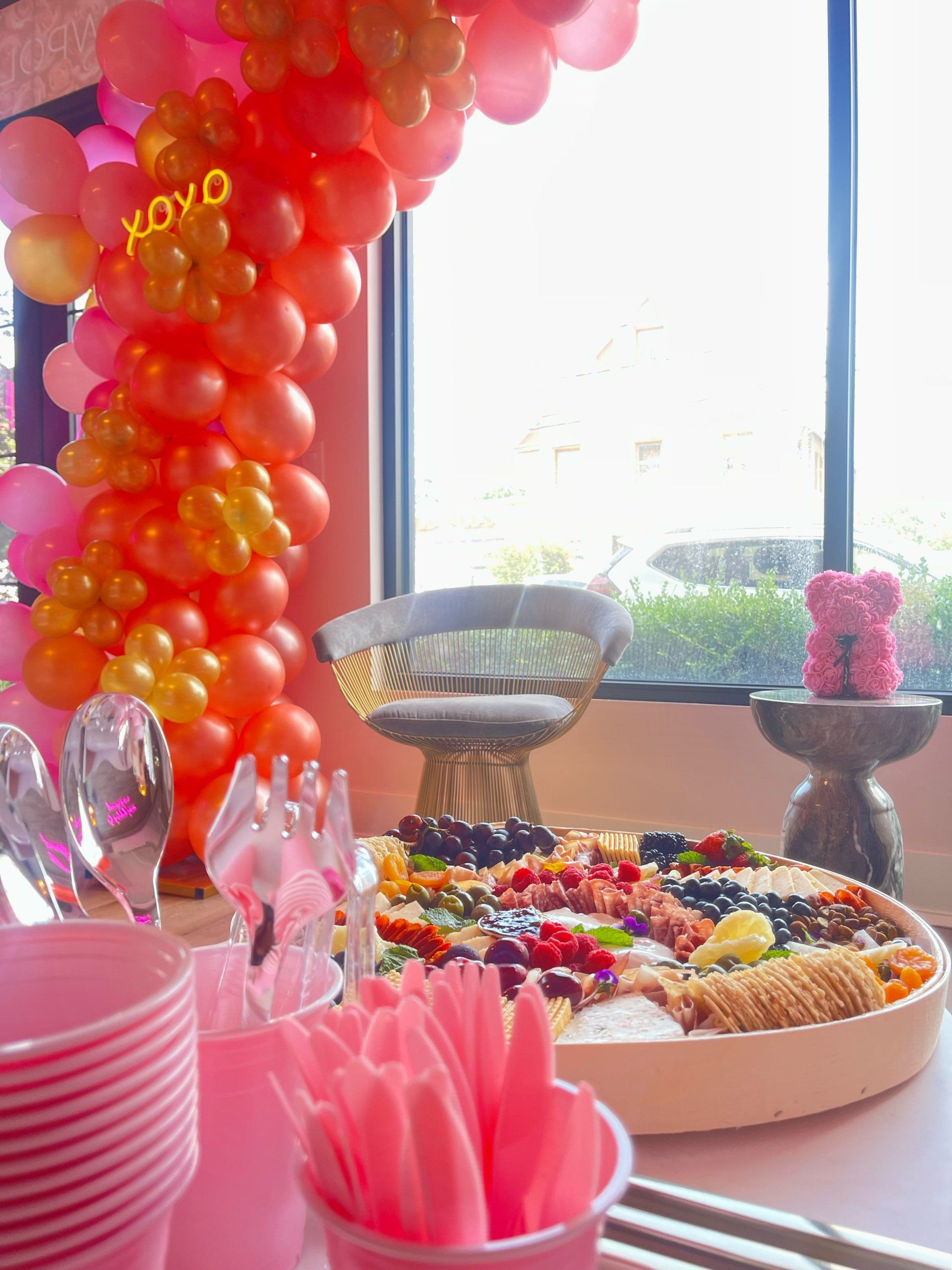 A table with a tray of food and balloons that say xoxo