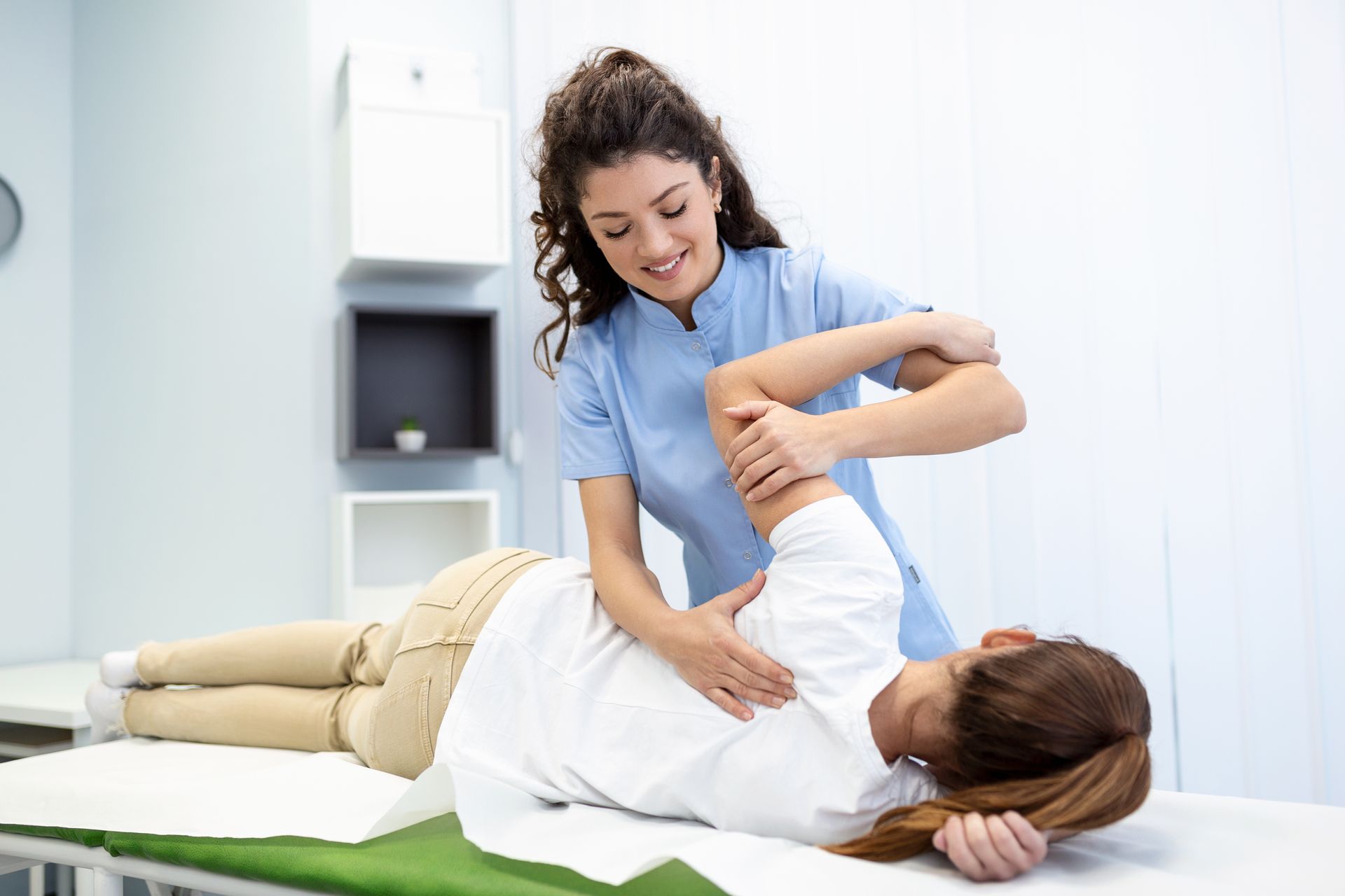 Physical therapist assisting a patient with a back stretch on a treatment table