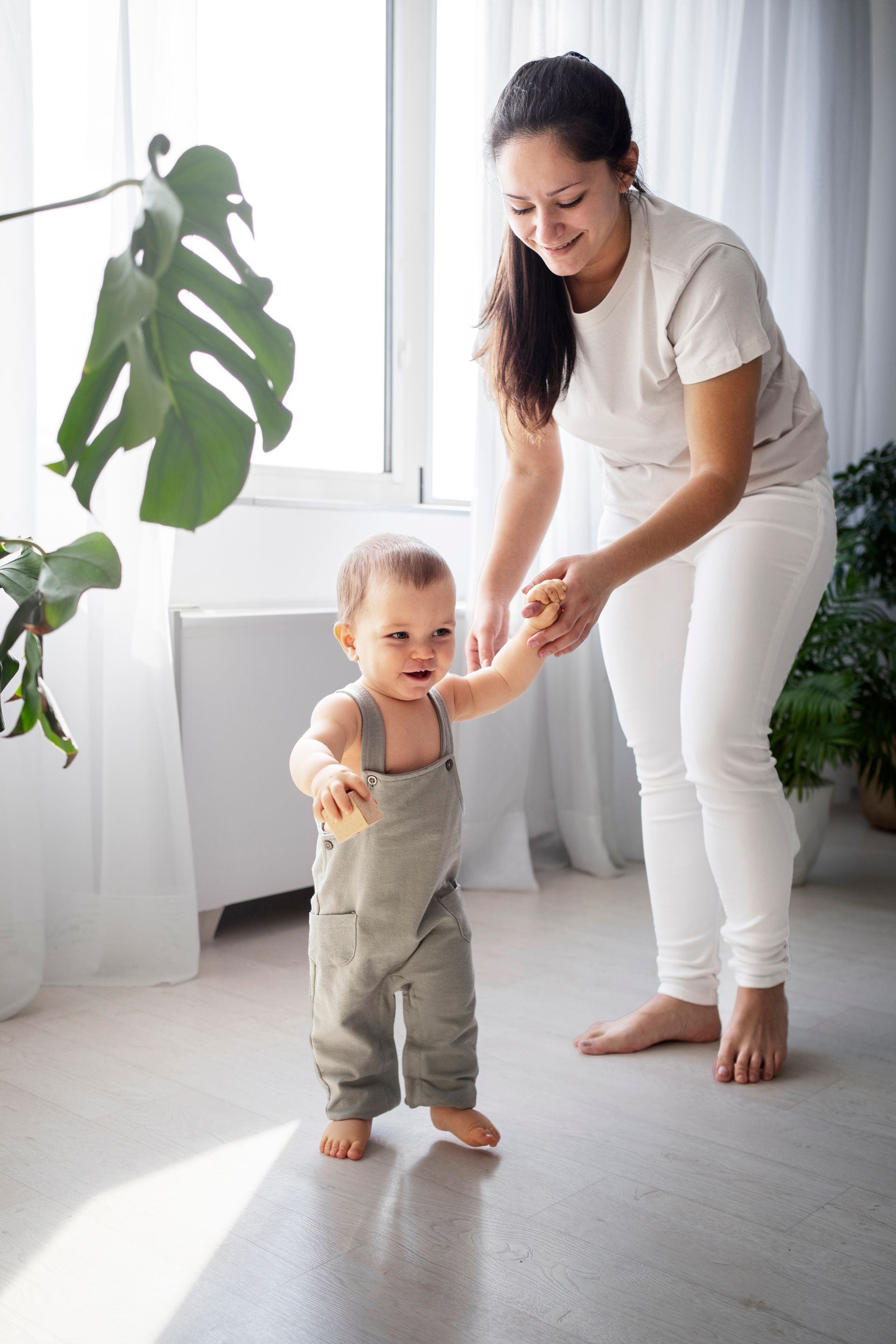 a woman is holding a baby 's hand as he tries to walk