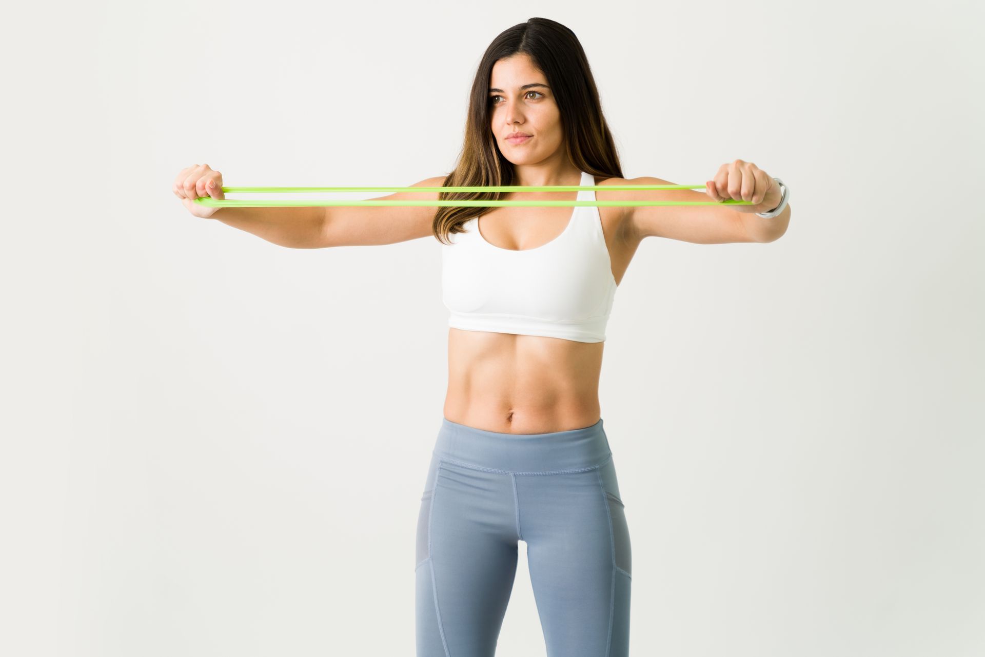 a woman is holding a green resistance band over her shoulder