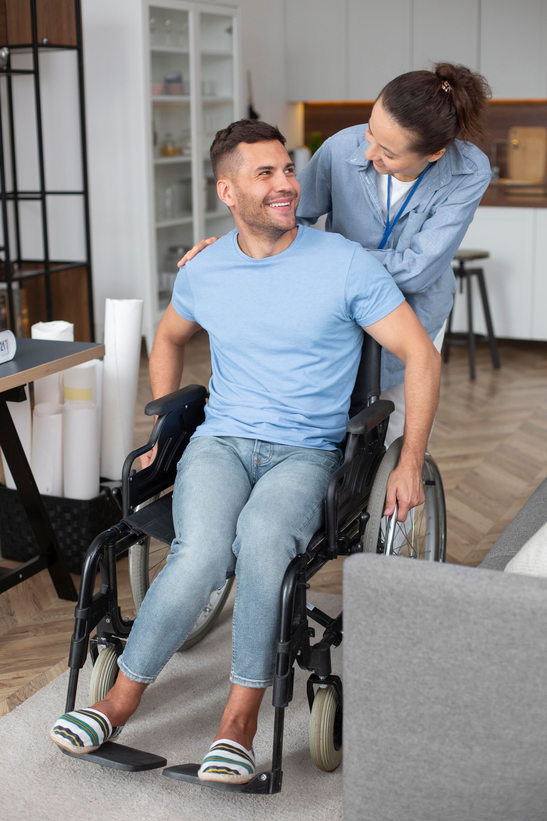 Woman helping a smiling man in a wheelchair at home