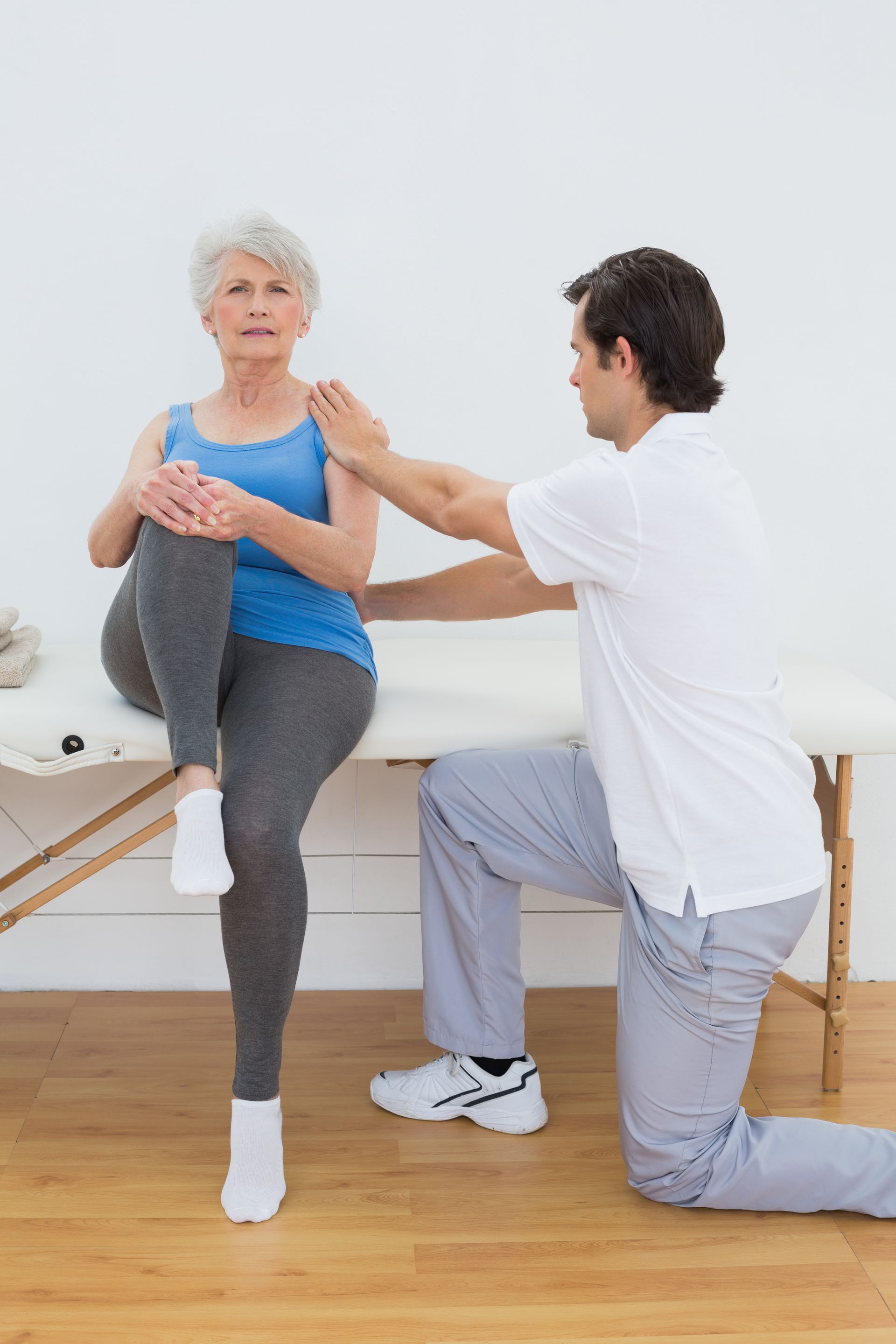 a man is helping an older woman stretch her leg
