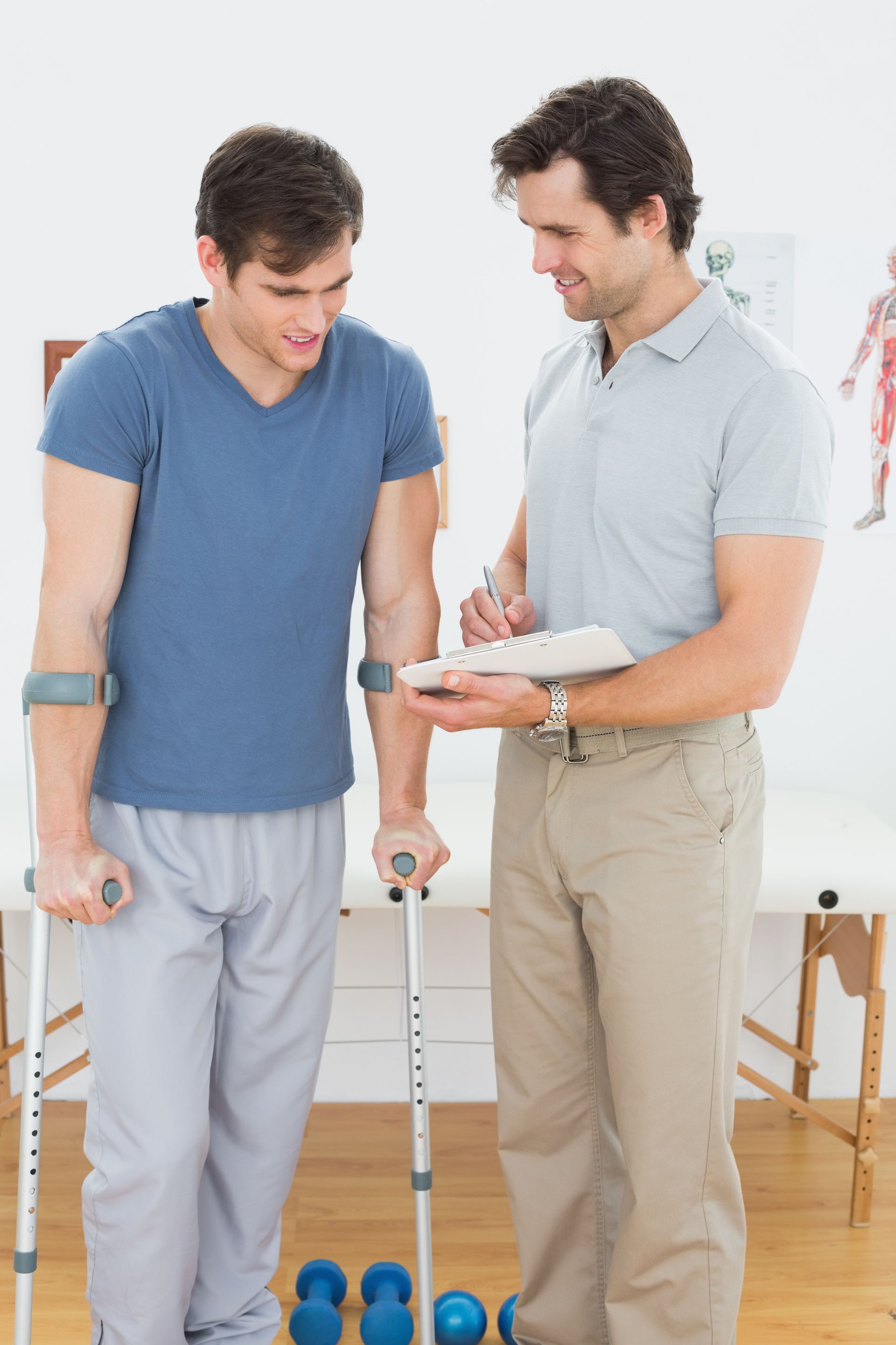 a man with crutches is talking to a man with a clipboard