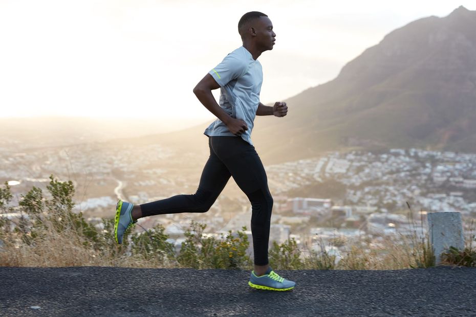 Runner jogging on a paved path with a mountain and cityscape in the background