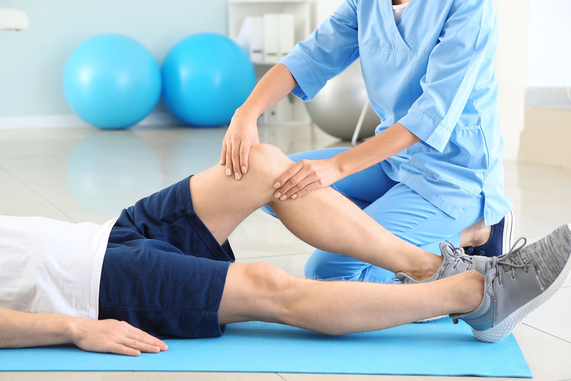 a man is laying on the floor while a nurse examines his knee