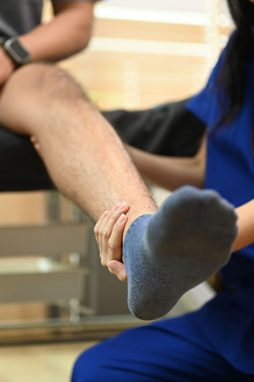 Close-up of a person holding another person’s lower leg and foot during a physical therapy session