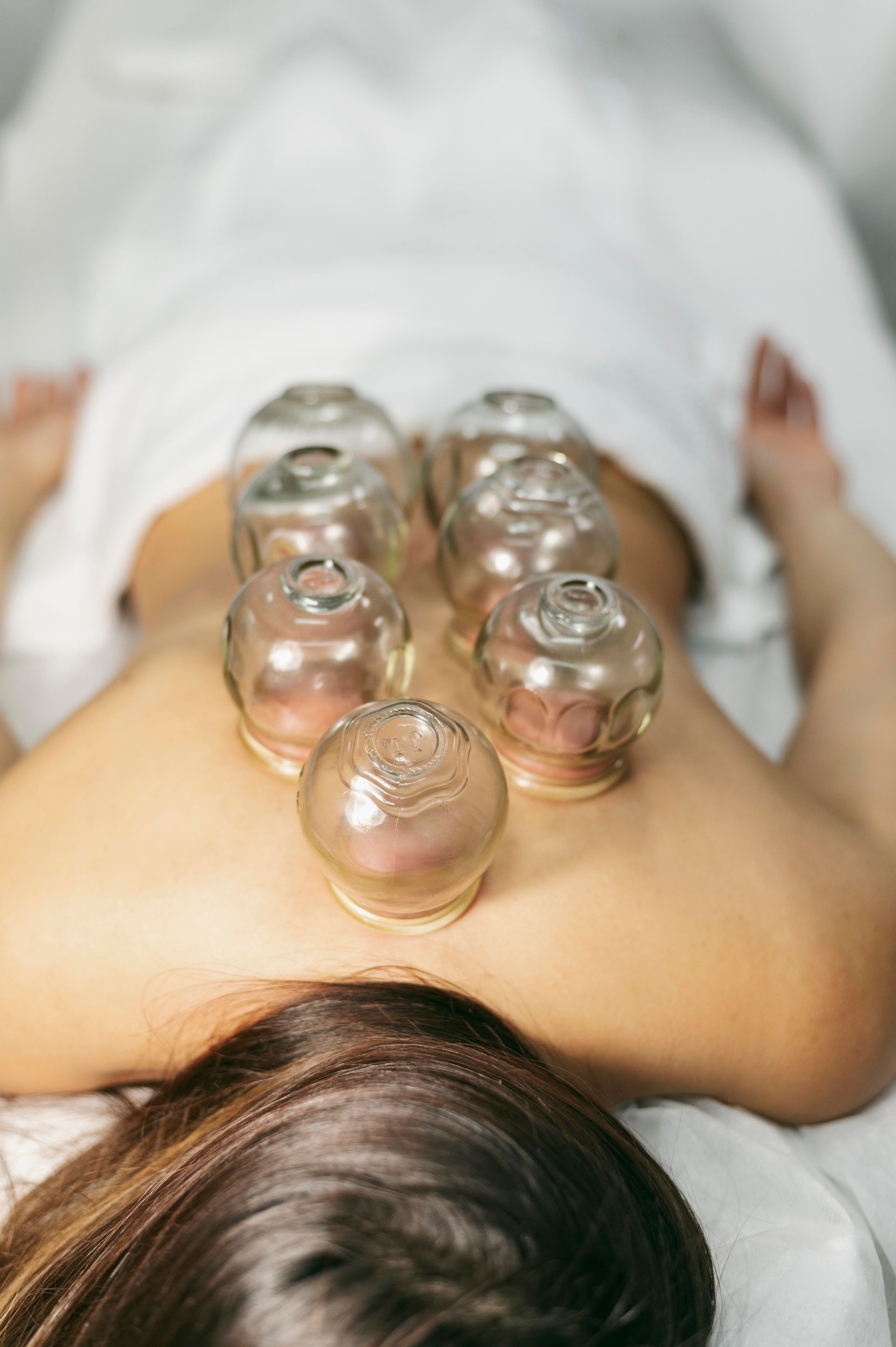 a woman is laying on a table with glass cups on her back