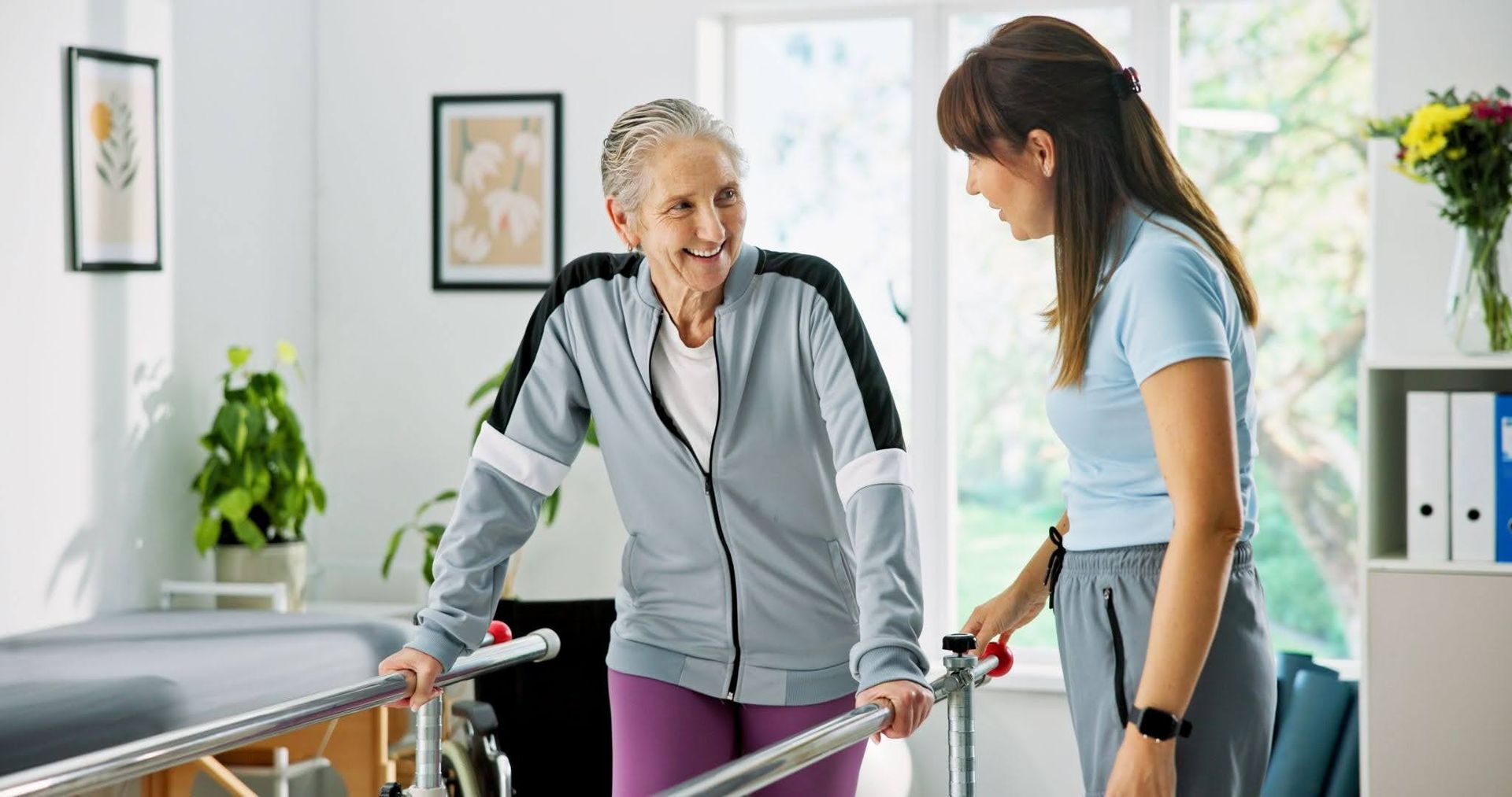 Woman helping an elderly patient walk with a walker in a bright home setting