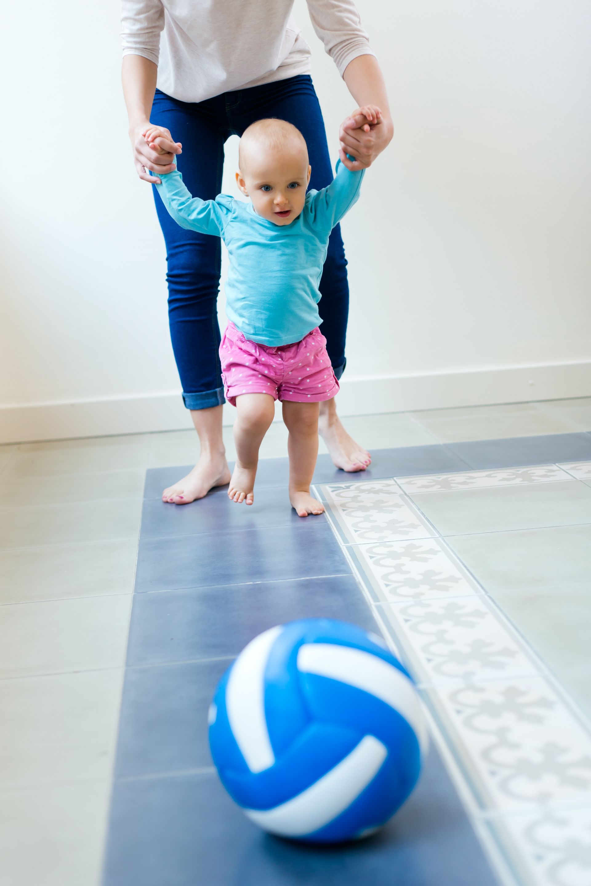 a baby is walking towards a blue and white volleyball