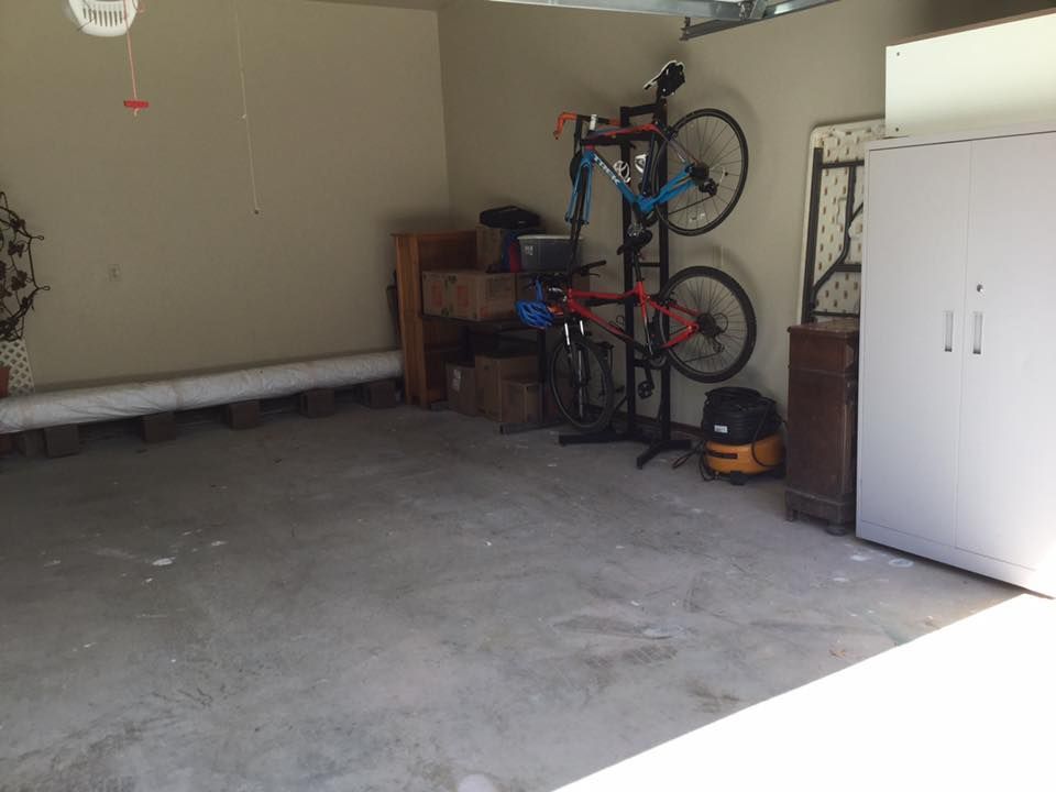 Garage interior: Concrete floor, bikes on stand, storage cabinet, boxes, and wall.