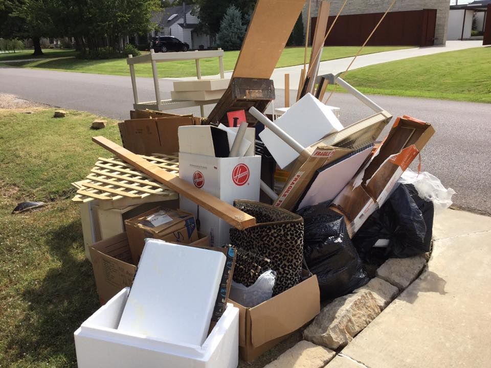 Pile of discarded household items, boxes, and trash on a curb, ready for pickup.