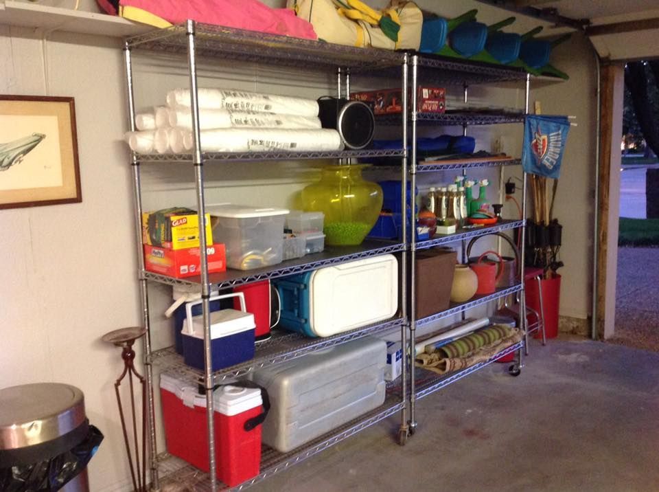 Metal shelving unit in a garage filled with various items like coolers, storage containers, and sporting equipment.