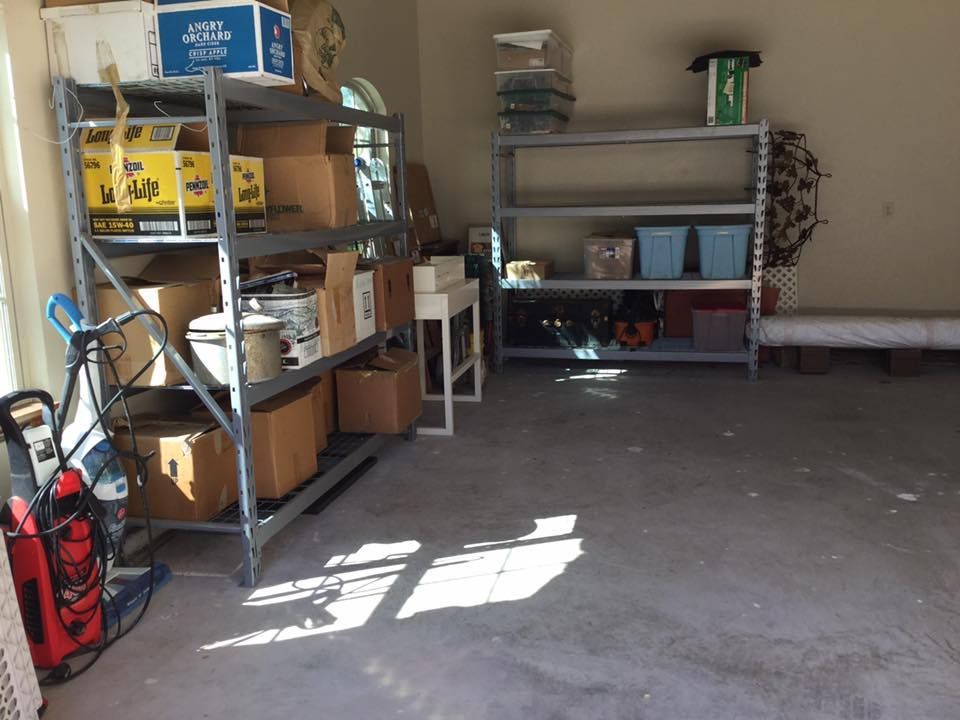 Garage interior with metal shelving filled with boxes, items, and storage bins. Concrete floor.