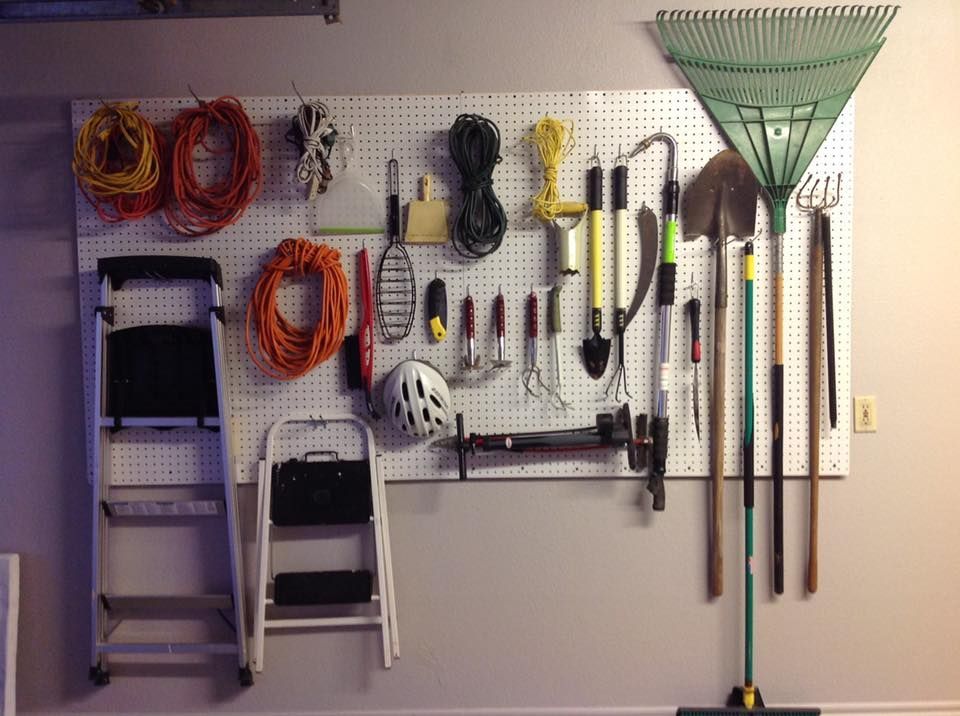 Pegboard wall with assorted tools and coiled cords in a garage, neatly organized.