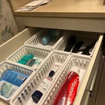 White bathroom drawer with various toiletries in labeled compartments.