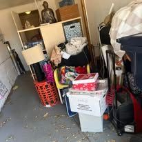 Cluttered storage area with boxes, furniture, and a statue.