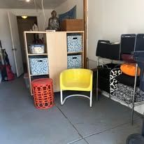Garage storage with shelves, chair, and a red stool.