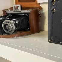 Vintage cameras and leather case on a white surface.