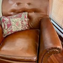 Brown leather armchair with a patterned pillow.
