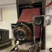 Close-up of a vintage camera with a red bellows and brass details.