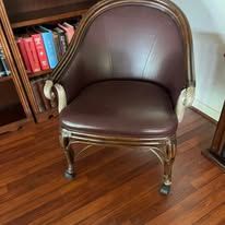 Leather armchair with a wooden frame, next to a bookshelf.