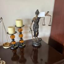Bronze Lady Justice statue and two candle holders on a table.
