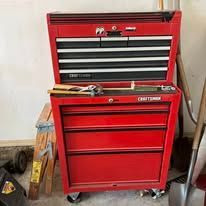 Red Craftsman toolbox with open drawers and a partially visible hand.