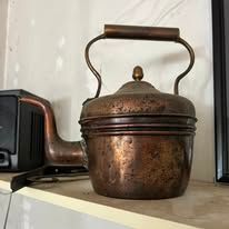 Copper kettle on a shelf, next to a vintage toaster.