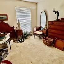 Bedroom with dresser, mirror, bench, and plants.