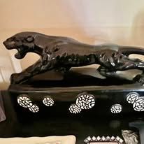 Black panther statue on a decorative base, with white floral accents.