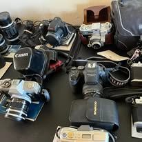 Several cameras and accessories on a black table.