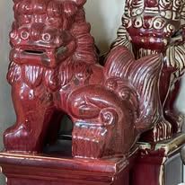 Two red ceramic guardian lion statues.