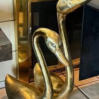 Gold brass swan statue pair, next to fireplace.