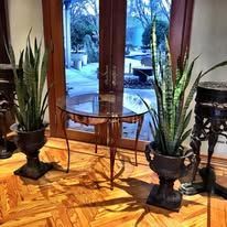 Two potted plants flank a round table in front of a glass door.