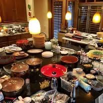 A cluttered kitchen table with various dishes, pots, and pans, likely after a meal.