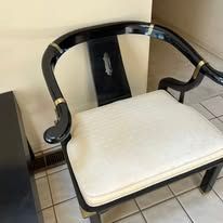 Black lacquer Chinese-style chair with ivory cushion, brass accents, indoor setting.