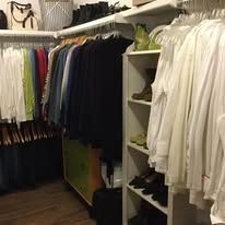 Walk-in closet with clothes hanging on racks; white and dark apparel.