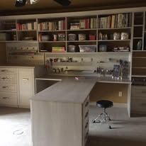 Built-in shelving unit with books, decor, and an island with a stool in a well-lit room.