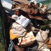Pile of cluttered trash including boxes, fabric, and other debris.