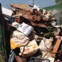 Pile of trash in a container, including wood, bags, and a partially visible appliance.