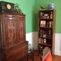 Wooden cabinet with a clock, bookcase, and green wall.