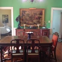 Dining room with table set for guests and large art piece.