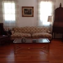 Living room with a floral sofa, wooden coffee table, and a framed landscape painting.
