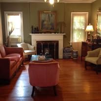 Living room with a fireplace, couches, and a pink armchair.