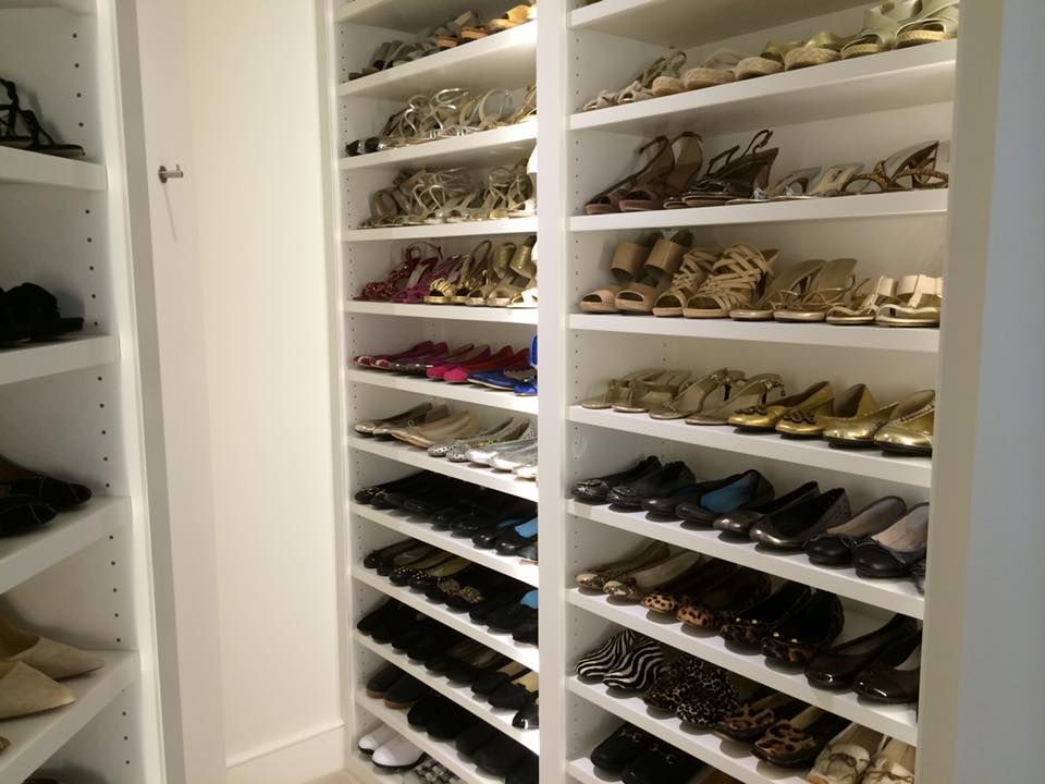 White shoe shelves filled with various women's shoes in a closet.