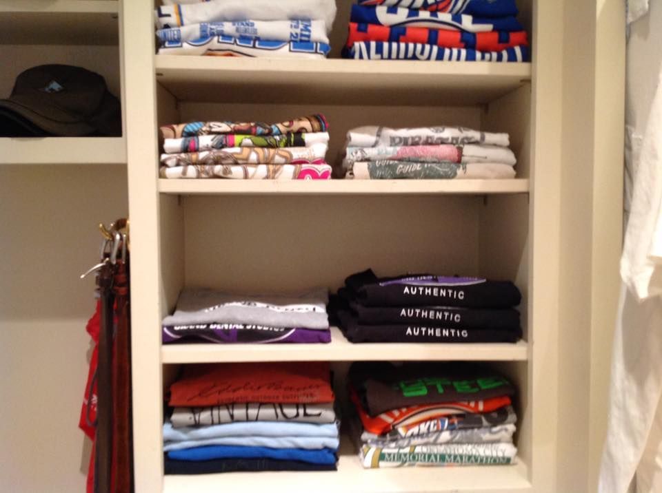 Shelves filled with neatly folded shirts of various colors, hats, and hanging clothing.