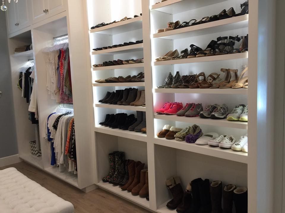 White closet filled with shoes and hanging clothes, brightly lit.